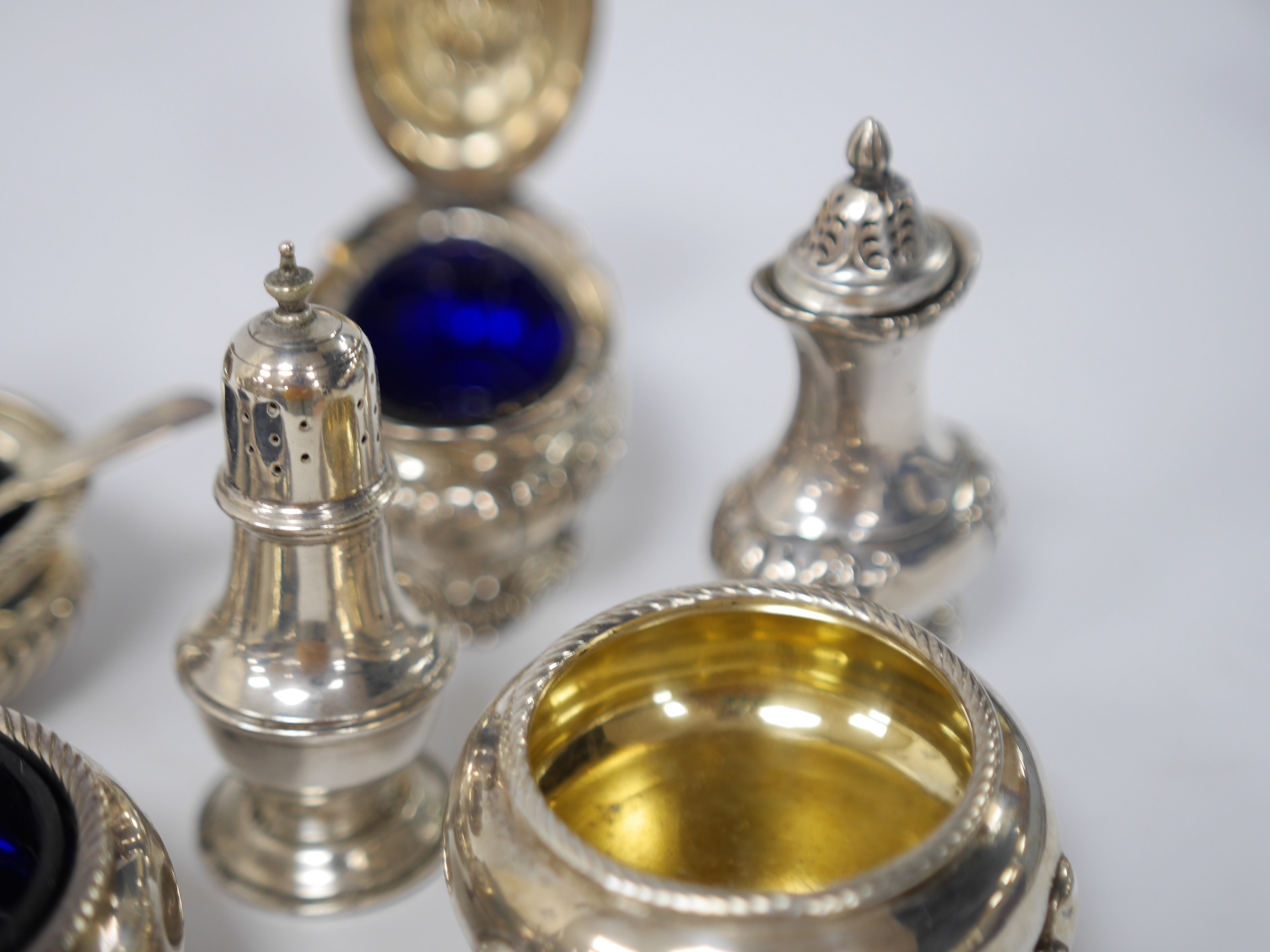 A pair of late George III silver circular salts, London, 1817, together with six later assorted silver condiments. Condition - poor to fair